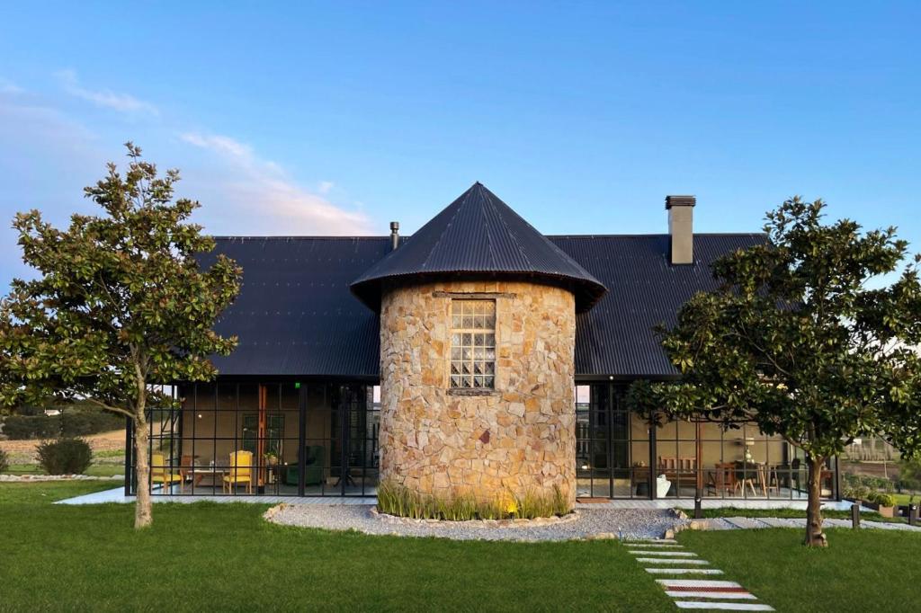 - un bâtiment en pierre avec un toit noir dans l'établissement ROCCHETTA HOTEL BOUTIQUE, à Sierra de los Padres