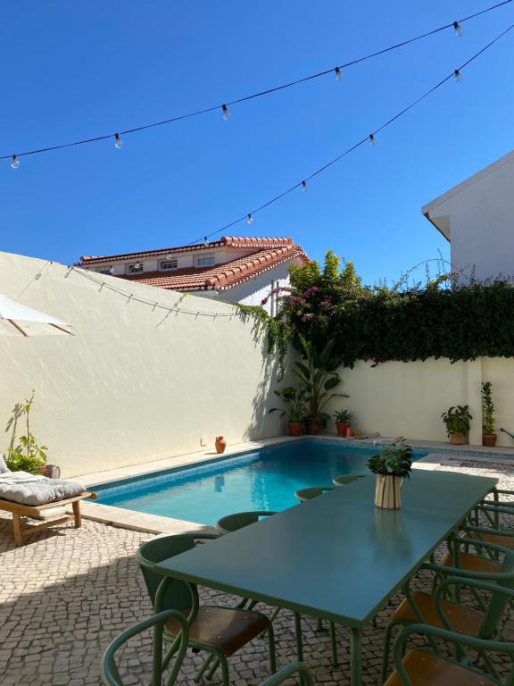 un patio con tavolo, sedie e piscina di Beach house upscale villa with pool a Costa da Caparica