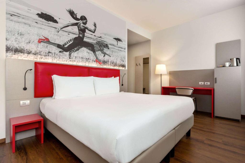 a hotel room with a large bed with a red headboard at Amedia Milan, Trademark Collection by Wyndham in Milan