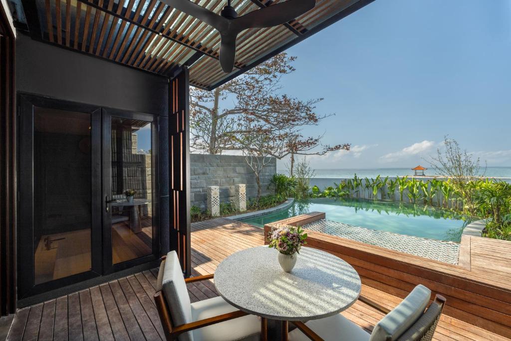 patio ze stołem i krzesłami oraz basenem w obiekcie Sumitra Luxury Villas A Pramana Experience w mieście Sanur