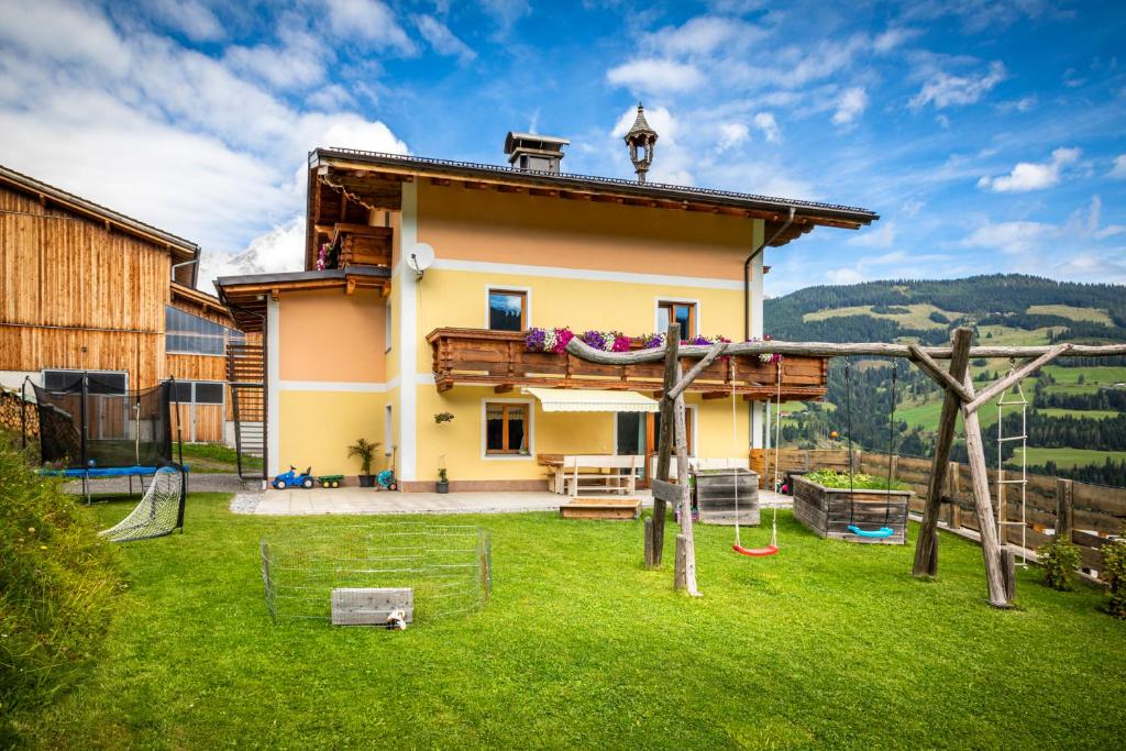 uma casa com um parque infantil no quintal em Brennergut Ferienwohnung am Bauernhof em Mühlbach am Hochkönig