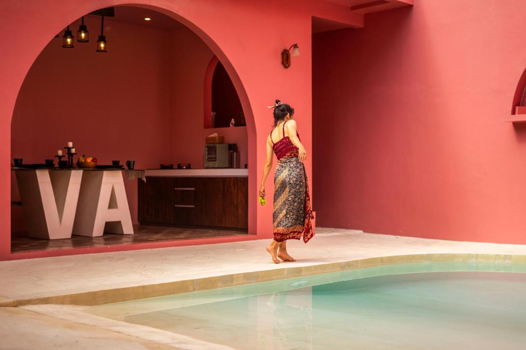 une femme en robe debout à côté d'une piscine dans l'établissement VA Villa Jimbaran Bali, à Jimbaran