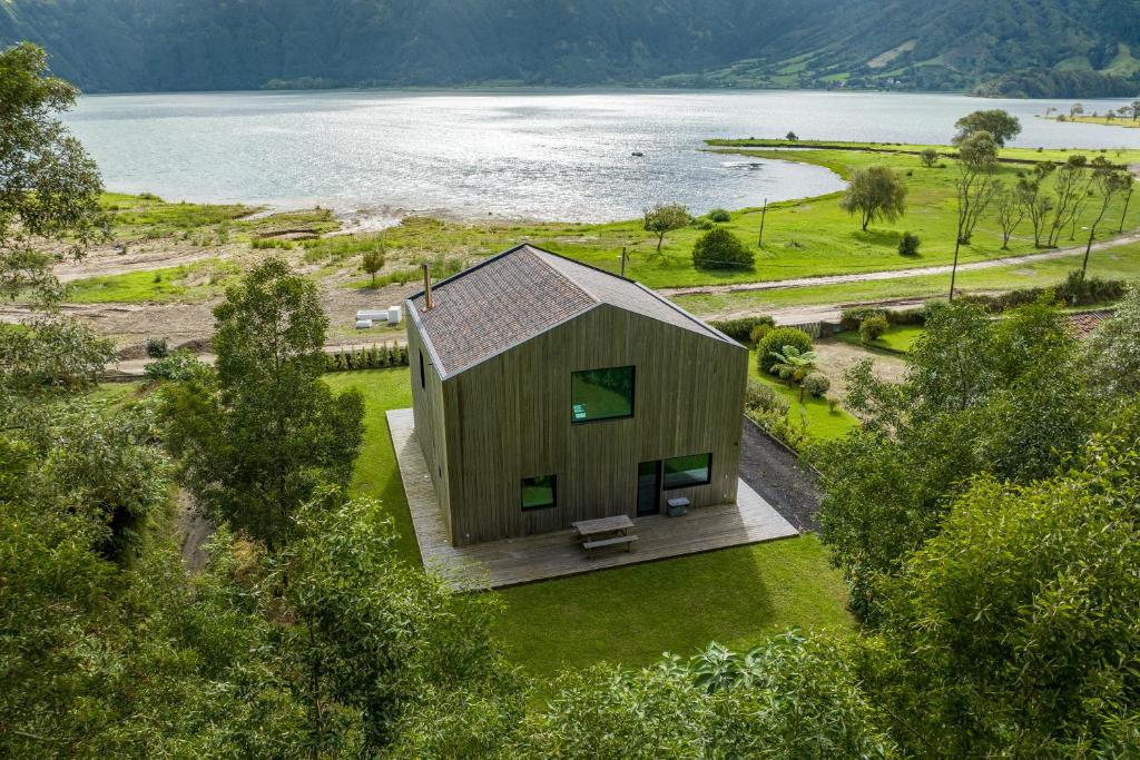 een klein houten huis op een gazon naast een meer bij Sete Cidades Lake Cabin - Casa da Lagoa in Ponta Delgada