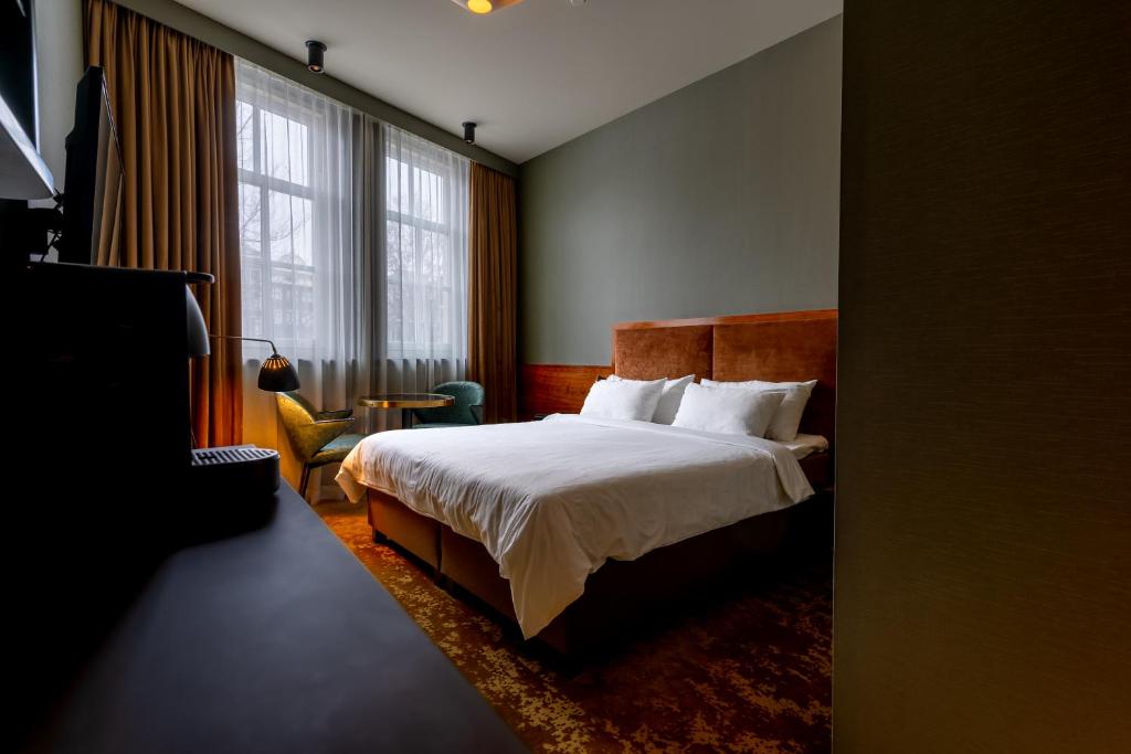 um quarto de hotel com uma cama e uma cadeira e janela em Hotel Mai Amsterdam em Amesterdão