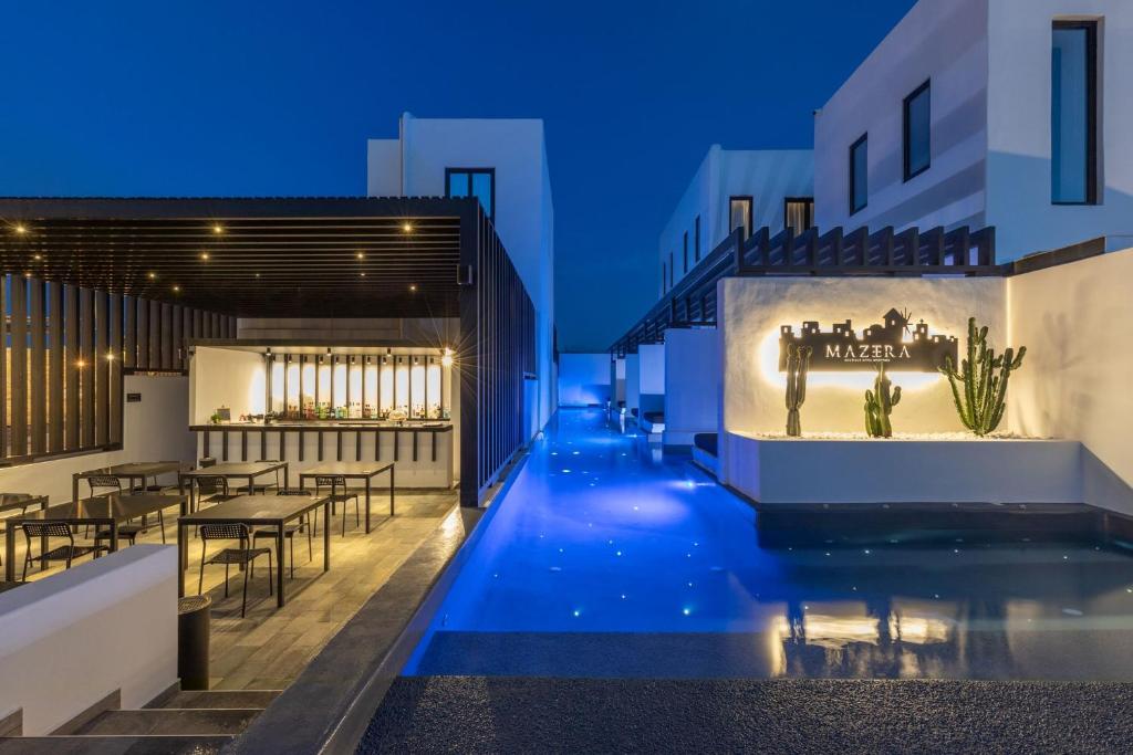 uitzicht op een zwembad in de nacht met een restaurant bij Mazera Boutique Hotel in Mykonos-stad