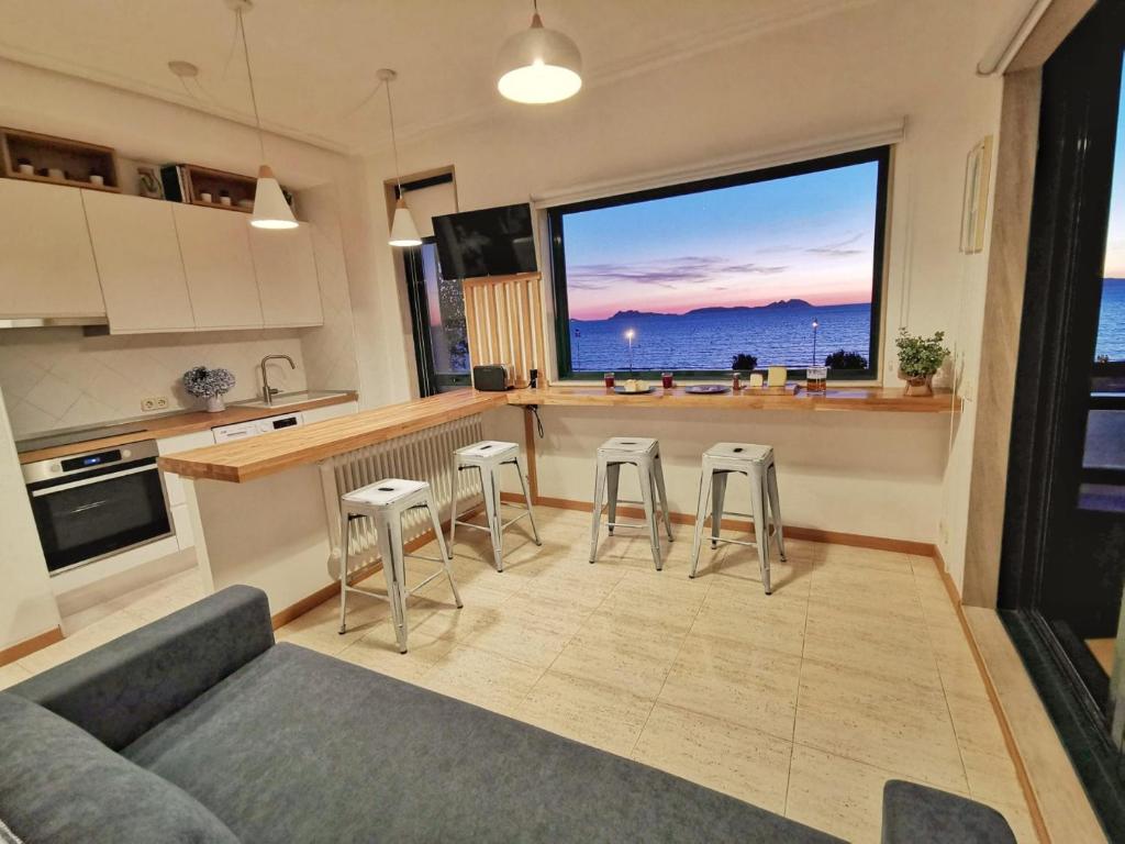 cocina con sofá, taburetes y ventana grande en apartamento Vigo Samil, en Vigo