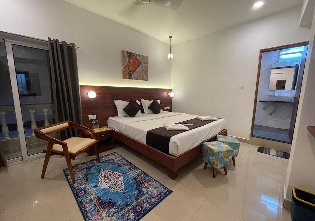 a bedroom with a bed and a chair and a mirror at Baga Keys by RJ14 in Old Goa