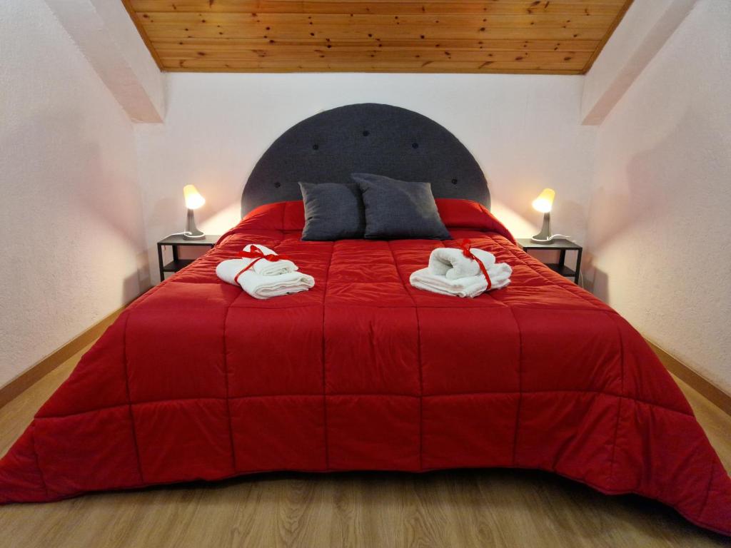 um quarto com uma cama vermelha e toalhas em [vicino impianti] - Aquila Reale em Sestriere