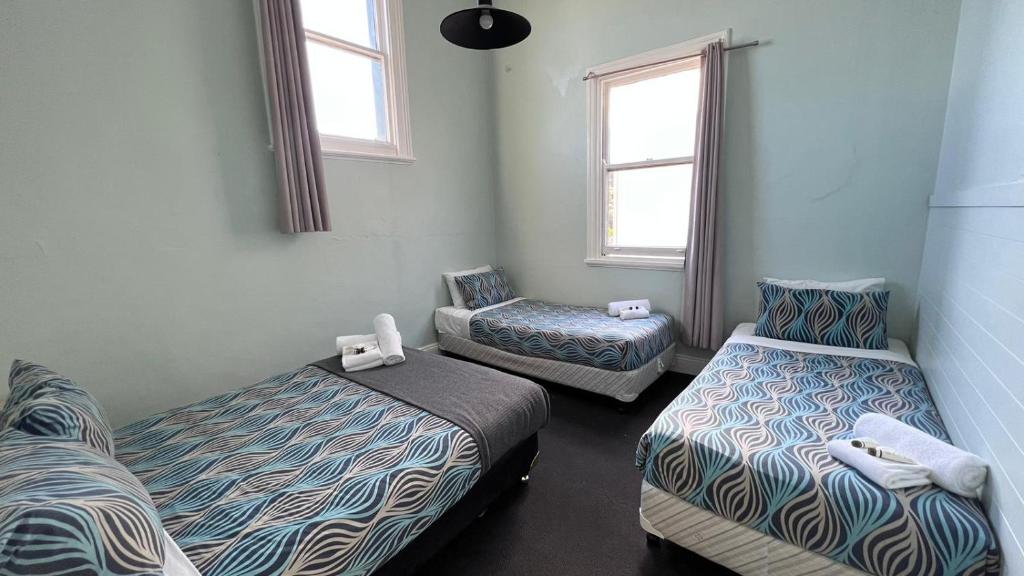 een kamer met 2 bedden en 2 stoelen. bij Beachside Budget Rooms in Kiama