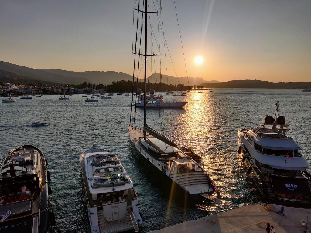 eine Gruppe von Booten, die bei Sonnenuntergang in einem Hafen anlanden in der Unterkunft The Manessi City Boutique Hotel in Poros