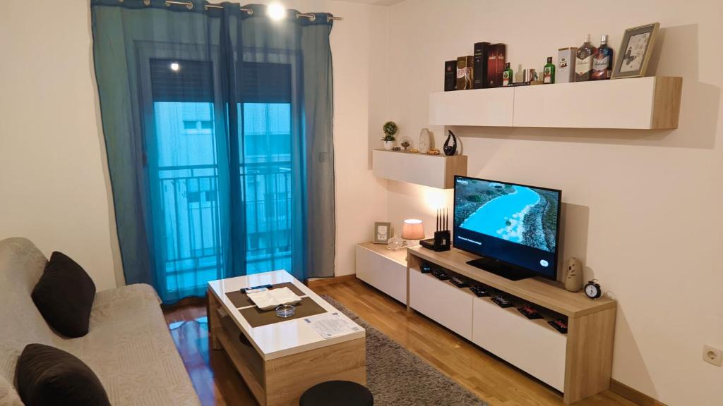 uma sala de estar com uma televisão de ecrã plano e um sofá em Guest House Mikeli (BESPL. DORUCAK)-(FREE BREAKFAST) em Podgorica