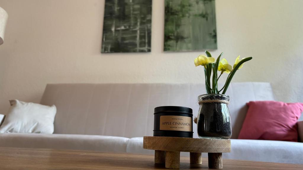 uma garrafa de vela e um vaso de flores sobre uma mesa em Bitterfelder Cityapartment im Dichterviertel em Bitterfeld