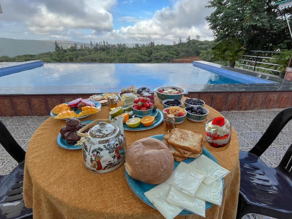 einen Tisch mit Essen drauf mit Blick auf den Pool in der Unterkunft Elsewhere Villa by Hill Staytion in Mahabaleshwar