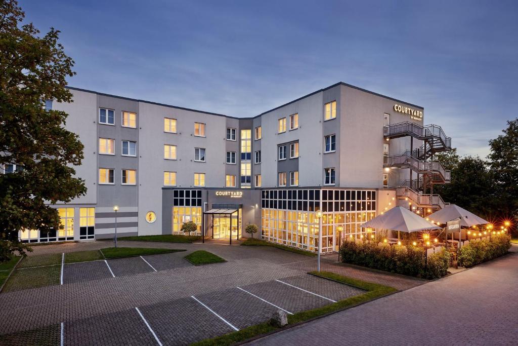 un bâtiment avec un court de tennis en face dans l'établissement Courtyard by Marriott Dortmund, à Dortmund