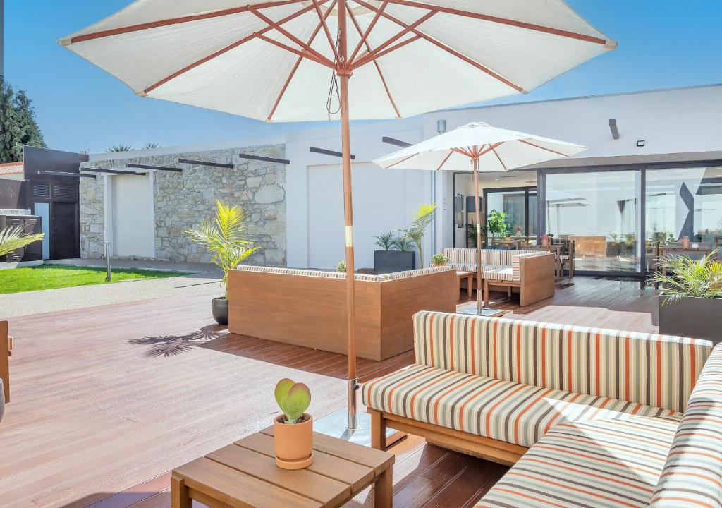 a patio with two couches and an umbrella at BFRESH Hotel - Padel, Pool & Fitness - Adults Only in Porto