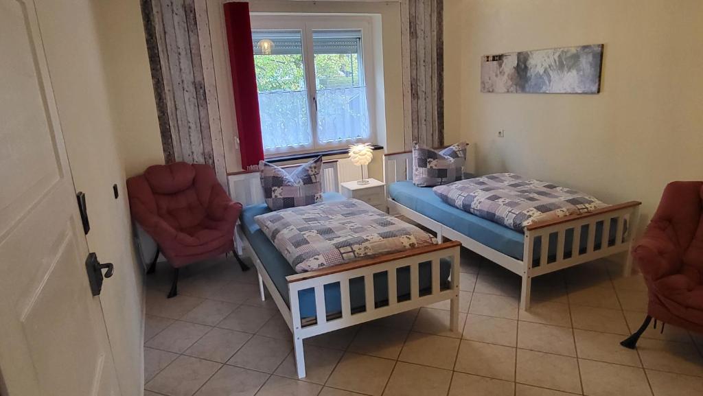 een kamer met 2 bedden, 2 stoelen en een raam bij Haus Adelheid in Weil am Rhein