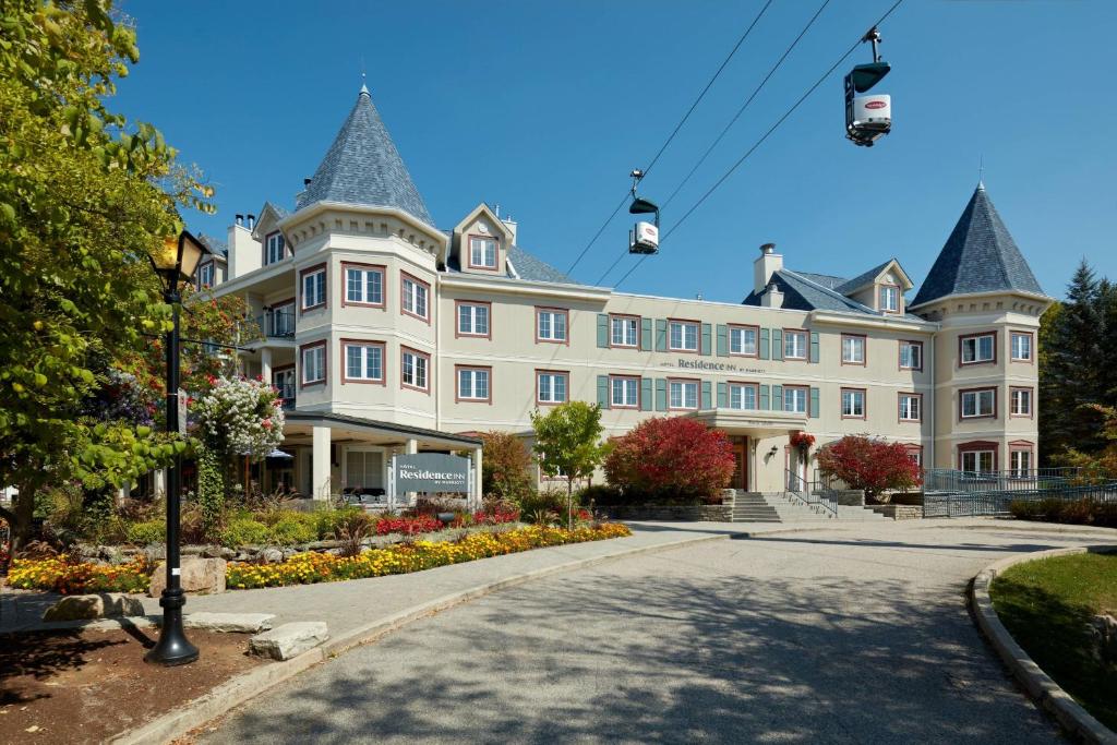 ein großes weißes Gebäude mit einer Straße davor in der Unterkunft Residence Inn by Marriott Mont Tremblant Manoir Labelle in Mont-Tremblant