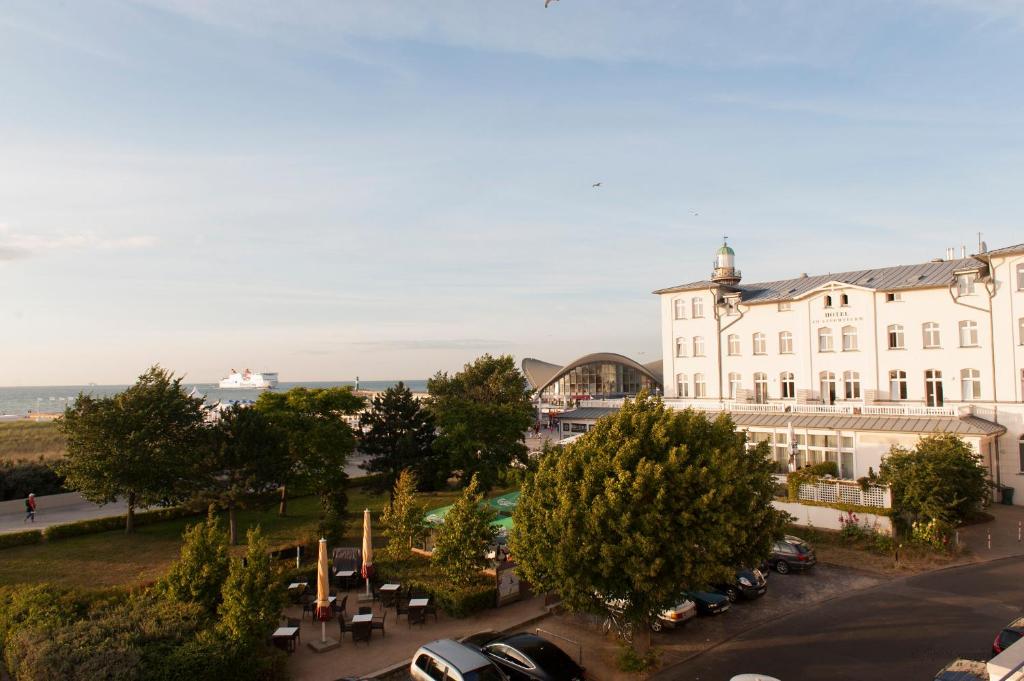 duży biały budynek z samochodami zaparkowanymi na parkingu w obiekcie Villa Meerblick Warnemünde - Ferienwohnung mit Meerblick in erster Reihe zum Strand und Promenade w mieście Warnemünde