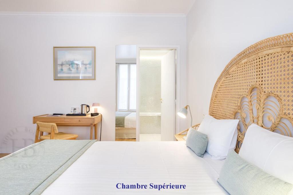 a bedroom with a white bed with a wooden headboard at Hotel Boileau in Paris