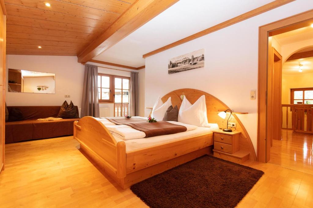 - une chambre avec un grand lit et un canapé dans l'établissement Ferienbauernhof Stallhäusl, à Fieberbrunn