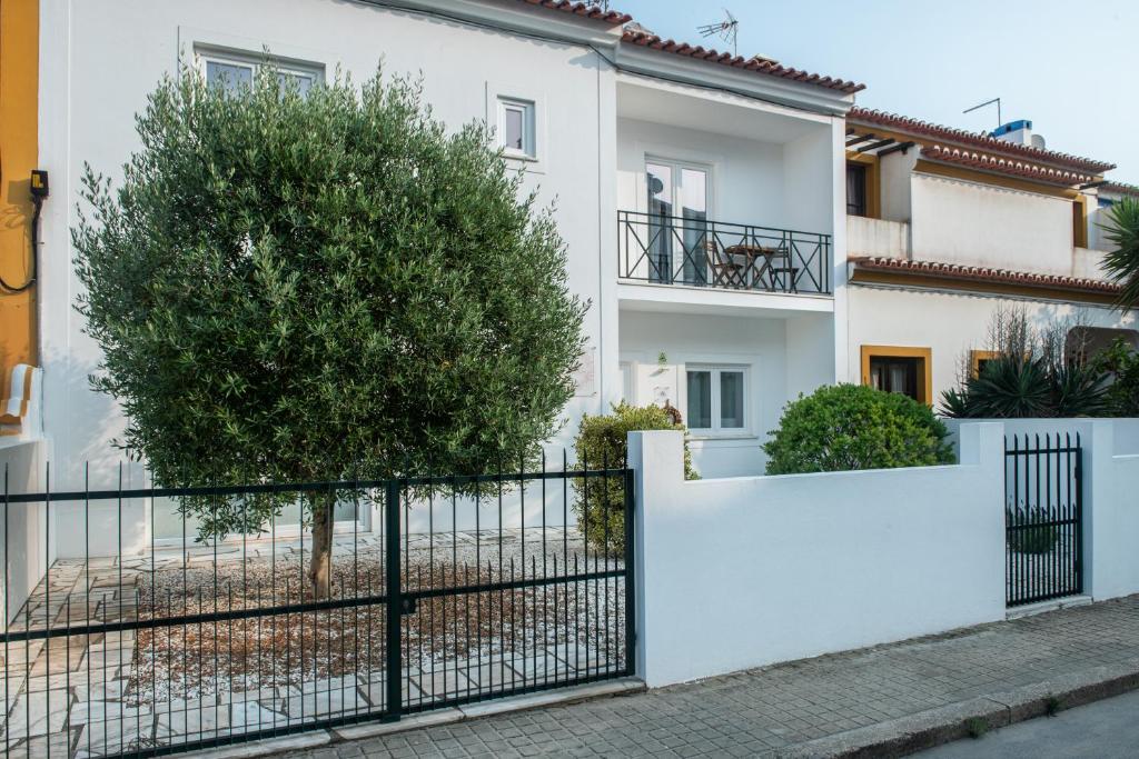 una casa bianca con una recinzione e un albero di Raminhos Guest House a Vila Nova de Milfontes