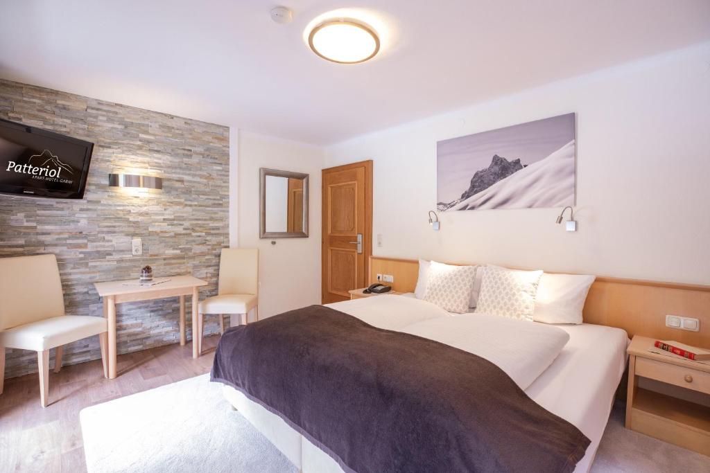 1 dormitorio con cama, mesa y TV en Patteriol Apart-Hotel-Garni, en Sankt Anton am Arlberg