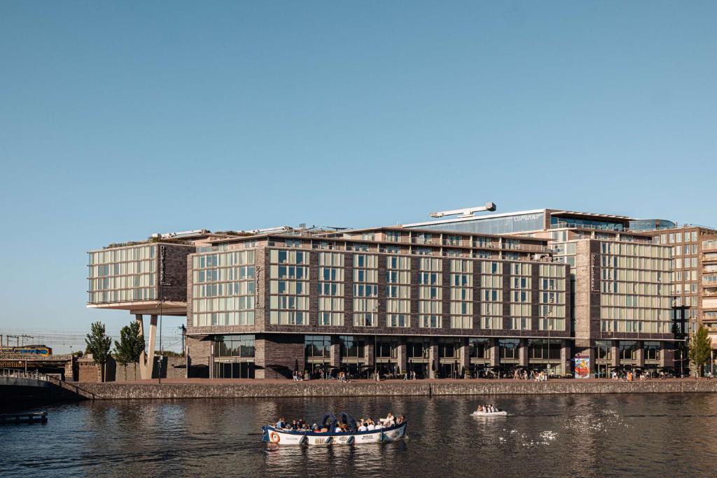 een groep mensen in een boot in een rivier met een gebouw bij DoubleTree by Hilton Amsterdam Centraal Station in Amsterdam