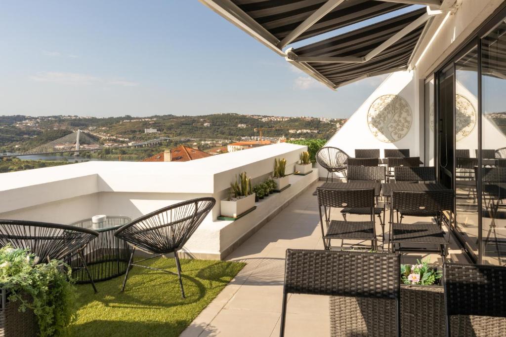 d'une terrasse sur le toit avec des chaises et des tables. dans l'établissement Penedo da Saudade Suites & Hostel, à Coimbra