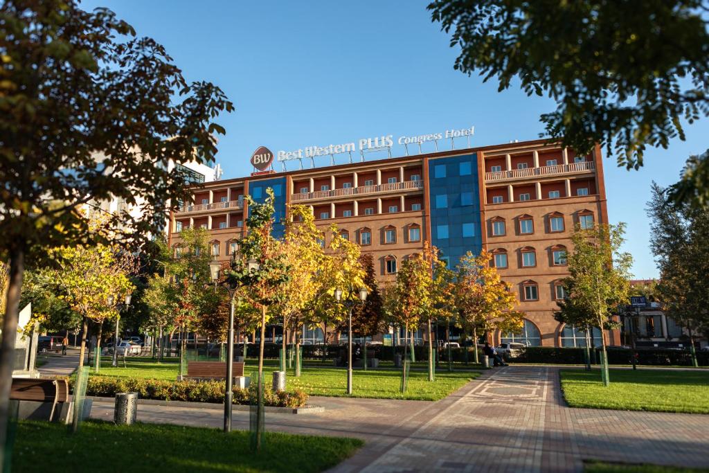 un edificio in un parco con alberi di fronte di Best Western Plus Congress Hotel Yerevan a Yerevan