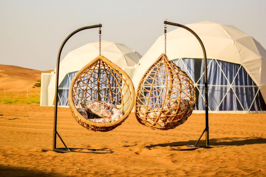 twee manden hangend aan palen voor de tenten bij Golden Desert Camp Al Wasil in Al Wāşil