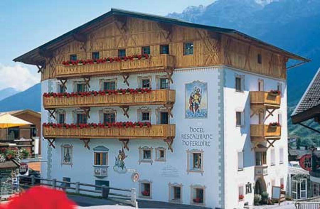 um grande edifício branco com um telhado de madeira em Hotel Hoferwirt em Neustift im Stubaital