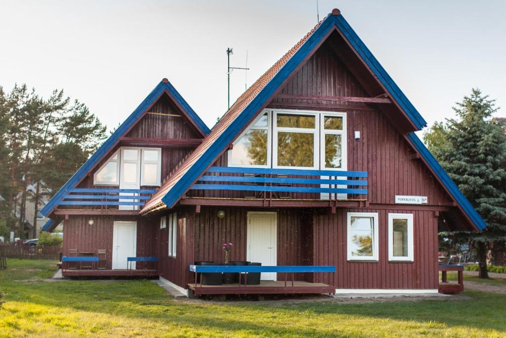 a red house with a blue roof at Pervalkos vetrunges in Neringa