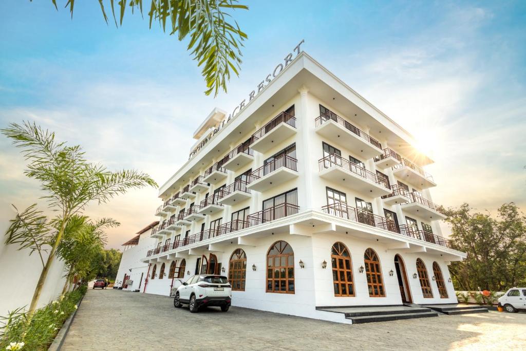 um edifício branco com carros estacionados em frente em Krown Palace Resort em Silvassa