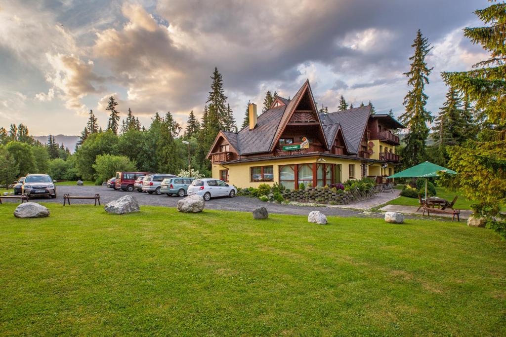 una grande casa con auto parcheggiate in un parcheggio di Penzión Ingrid a Štrbské Pleso