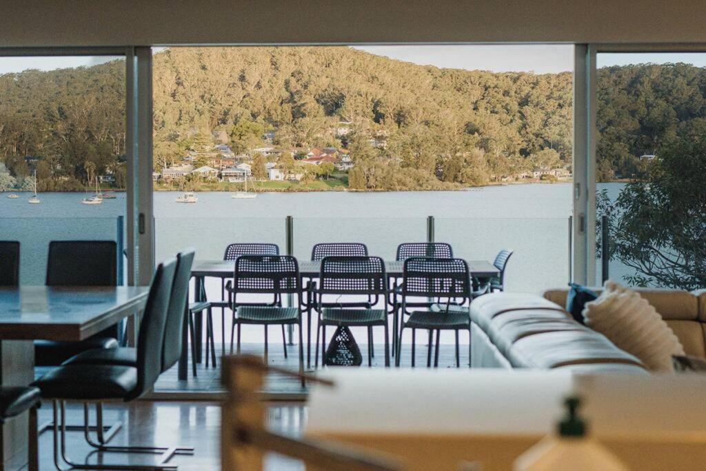 Cette chambre dispose d'une grande fenêtre et d'une table avec des chaises. dans l'établissement 11 East Gosford Luxury Waterfront House with Private Wharf, à Gosford