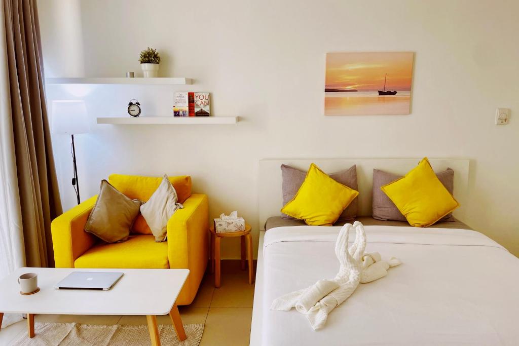 - une chambre avec un lit et un canapé jaune dans l'établissement Sunshine, à Ras al Khaimah