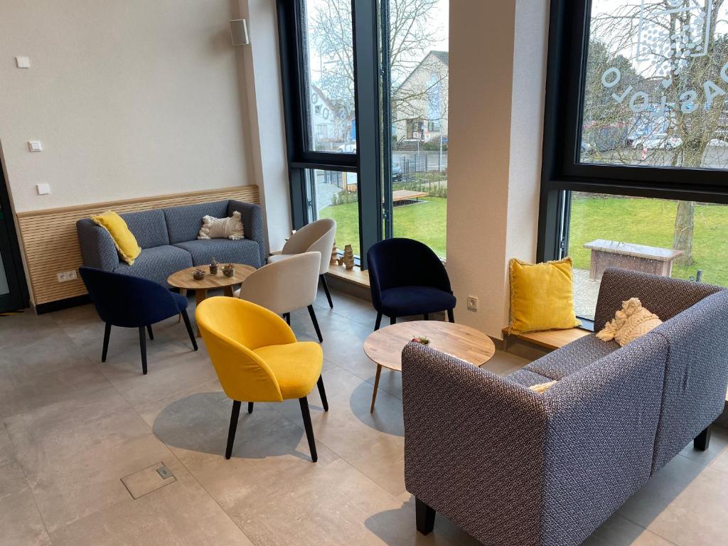 a waiting room with couches and tables and windows at Village Turmzimmer in Kehl am Rhein