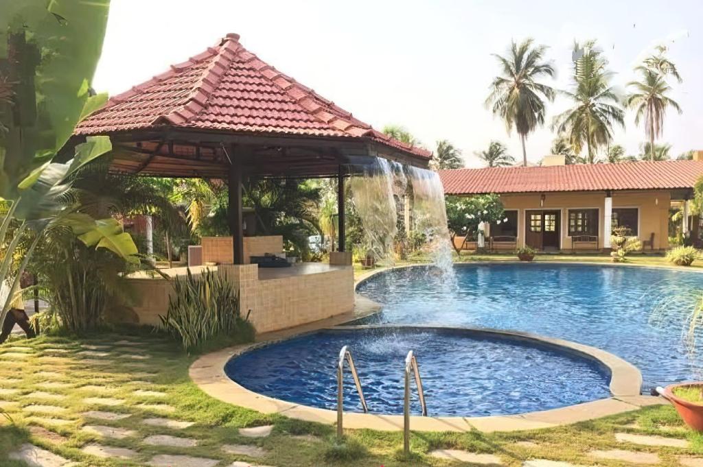 - une piscine en face d'une maison avec une cascade dans l'établissement Majorda Coastal Homestay, à Nuvem