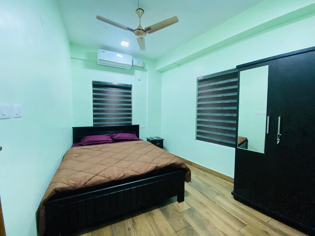 een slaapkamer met een bed en een plafondventilator bij AL-Kabeer Lavender budget rooms in Trivandrum