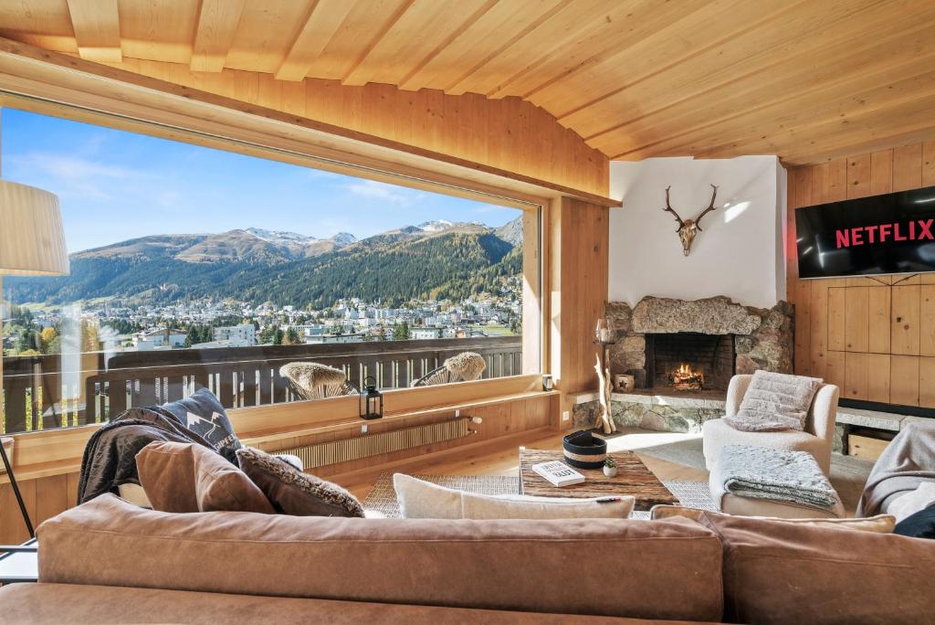 sala de estar con ventana grande con vistas a la montaña en A&Y Chalet zum goldenen Hirsch, en Davos