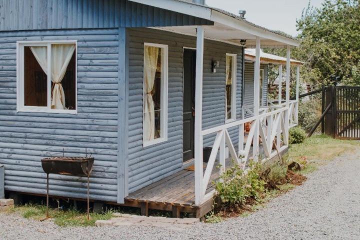 a blue house with a porch and a wooden porch at CABAÑAS TRAPEN in Puerto Montt