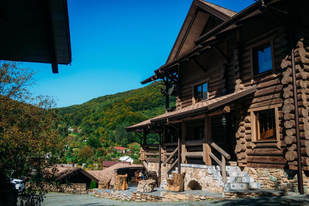 uma cabana de madeira com uma montanha ao fundo em BRB Park Hotel em Vizhenka