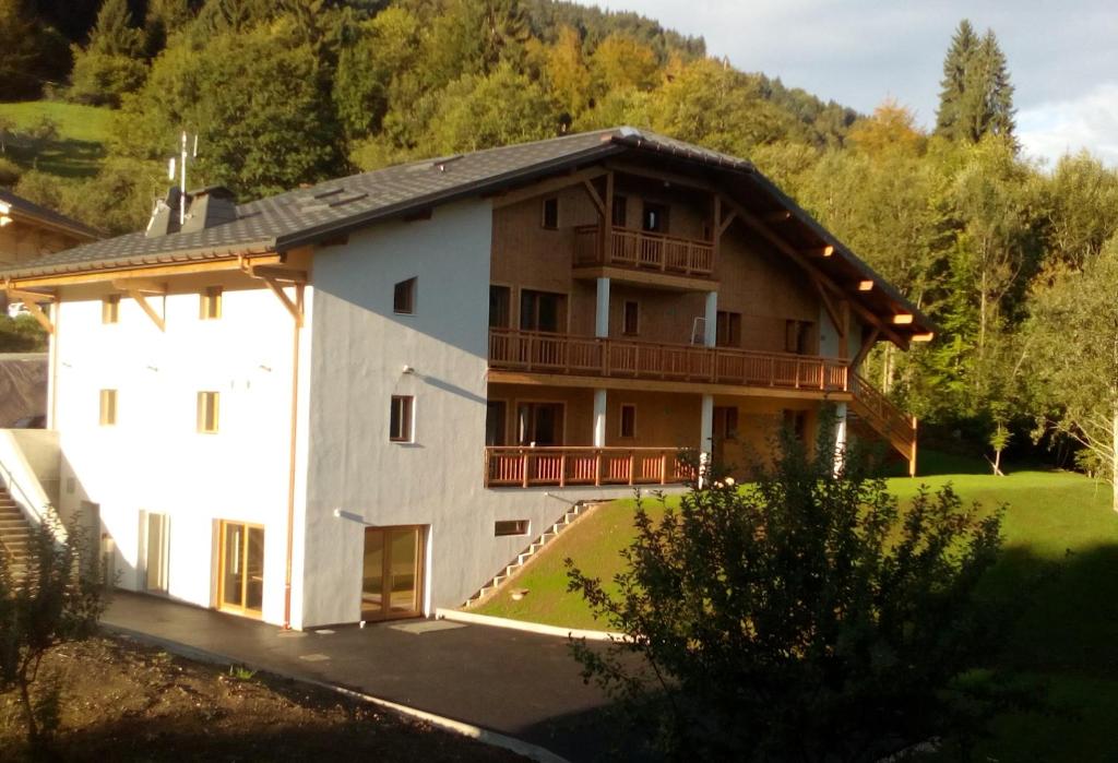 ein großes weißes Gebäude mit einem Balkon und Bäumen in der Unterkunft Chalet d'Arfeuille - Chambre 2 personnes in Samoëns