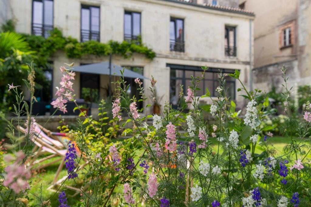 a garden with flowers in front of a building at Escale Rochelaise, chambre avec acces toute l'année au sauna et SPA chauffée in La Rochelle