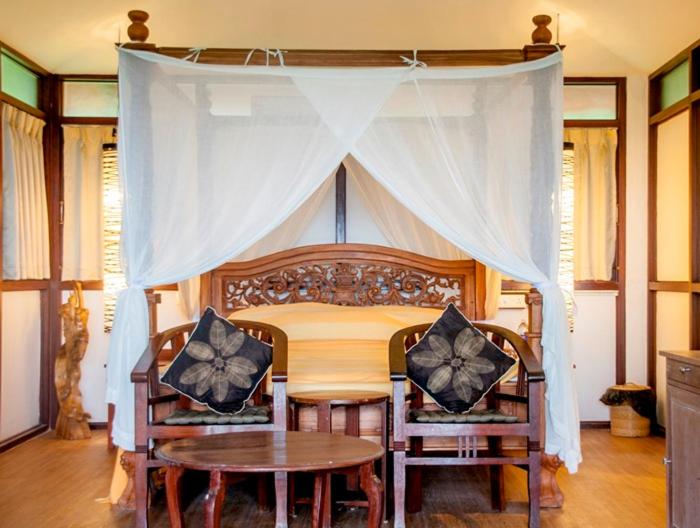 a canopy bed with two chairs and a table at Over The Hill in Pūvār