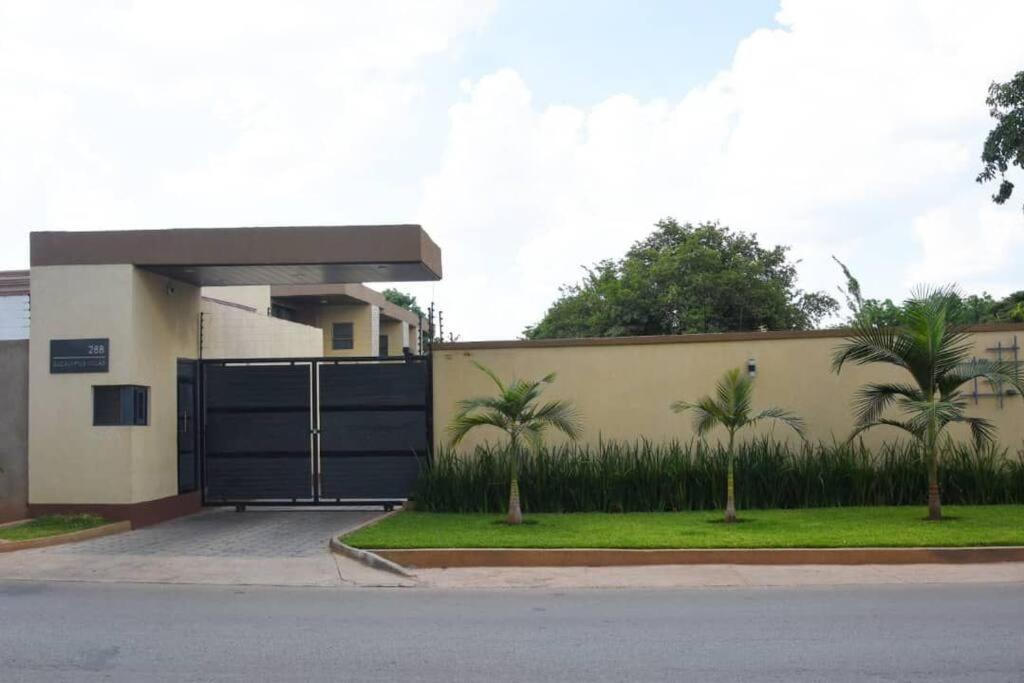 een gebouw met een hek met palmbomen ervoor bij Dk Casa in Lusaka