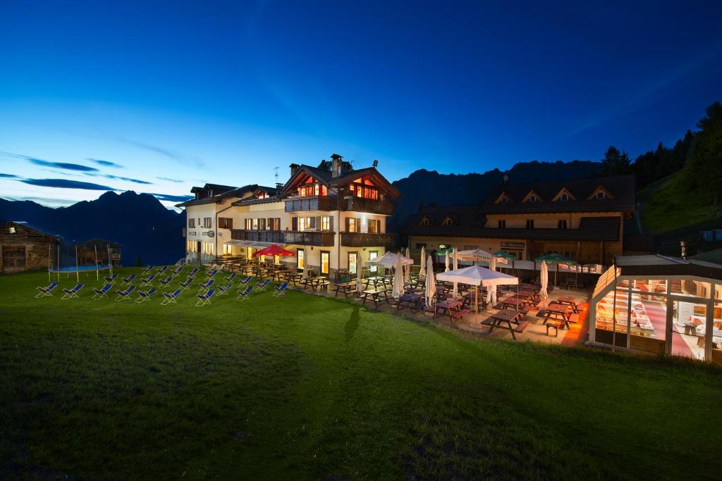 een groot gebouw met 's nachts tafels en stoelen bij Hotel Gallo Cedrone in Valdisotto