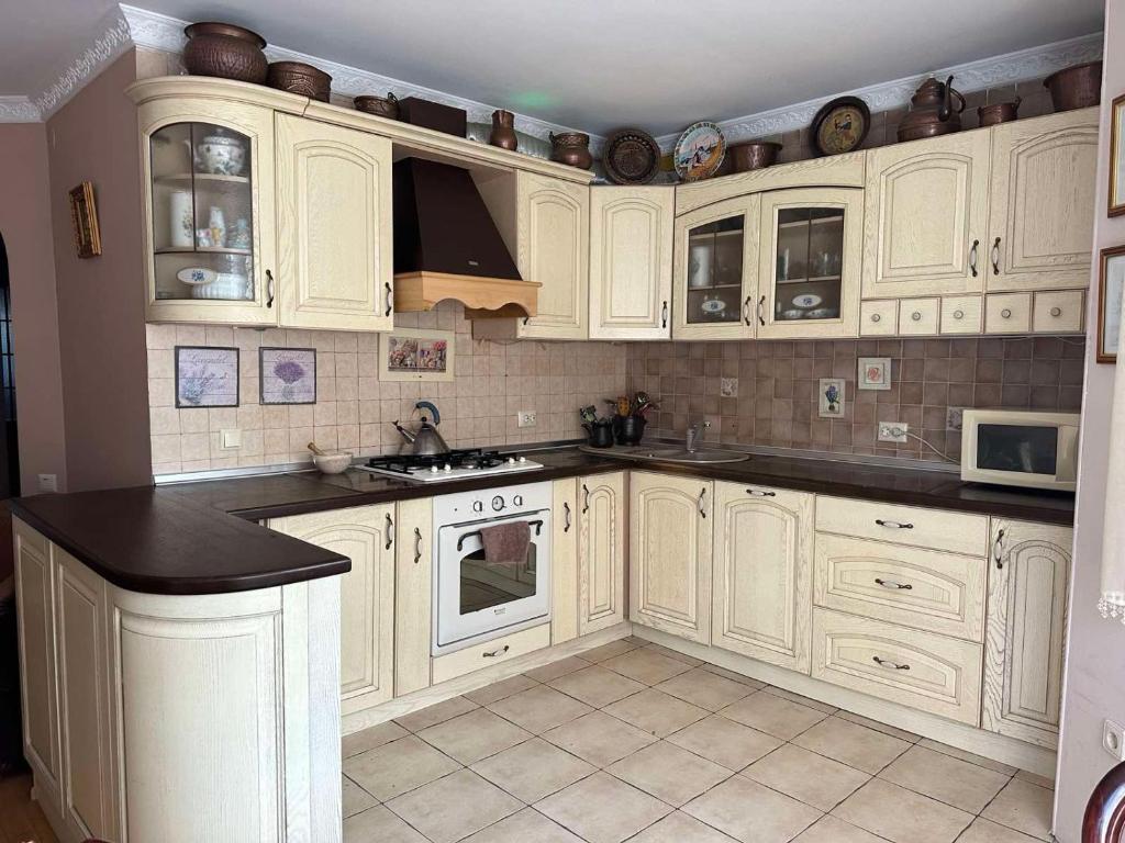 a kitchen with white cabinets and black counter tops at Rest house in Truskavets