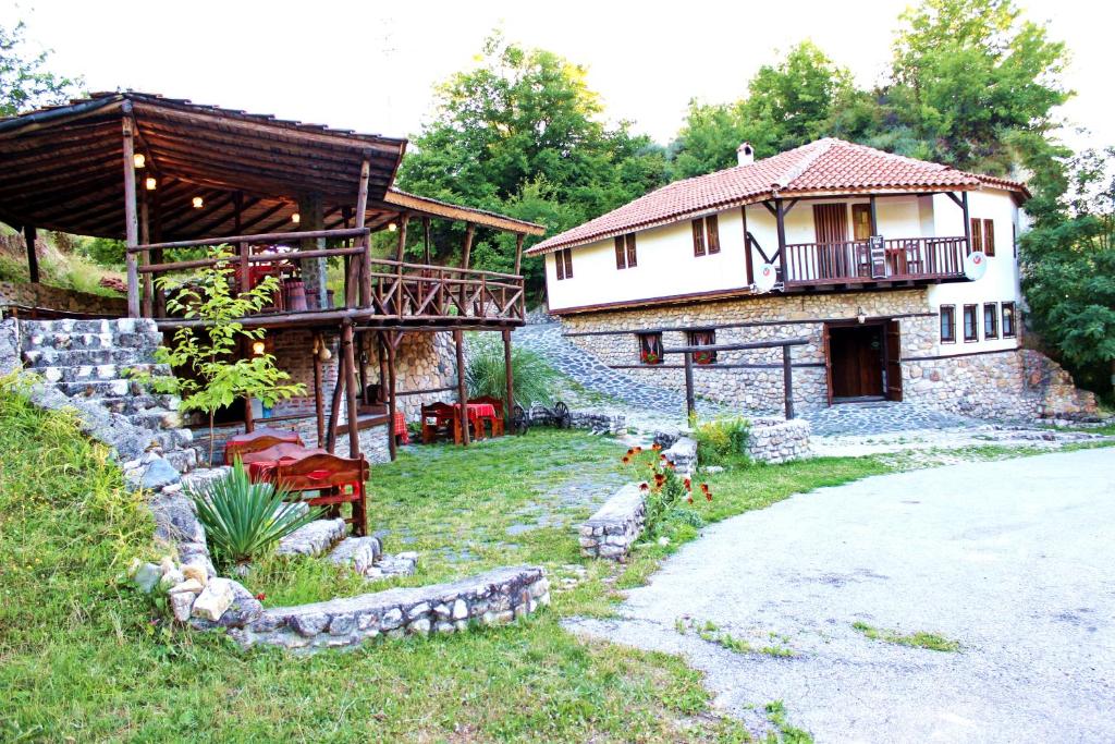 ein Haus mit einer Veranda und einem Gebäude mit einem Balkon in der Unterkunft Melnik Pyramids Guesthouse in Zlatkov Chiflik