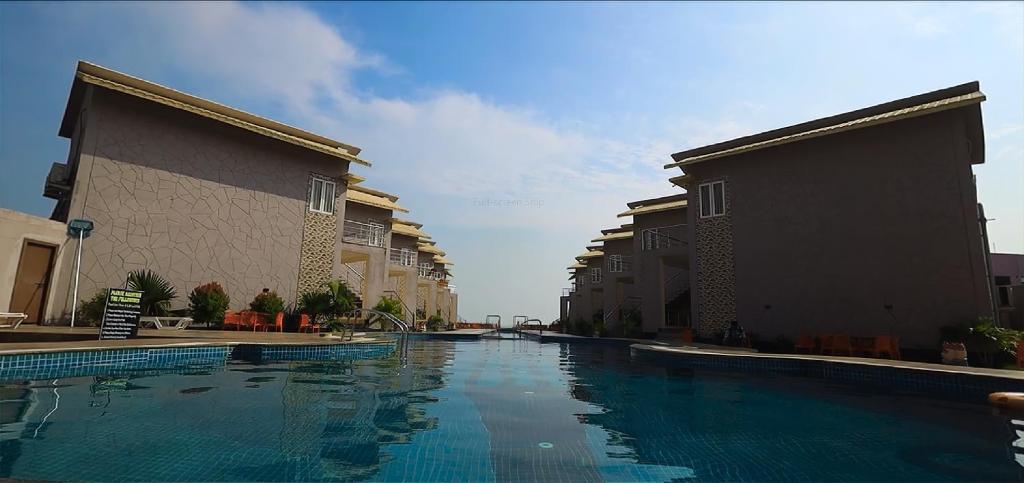 una piscina con acqua blu tra due edifici di Parth King Beach Resort a Mandarmoni